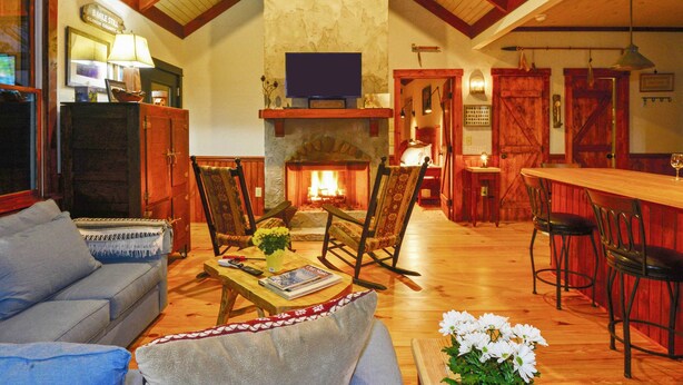 A cozy living room with a fireplace, wooden furniture, and a television. - Woodsy Bryson City Cabin w/ Smoky Mountain Views! (Bryson City)