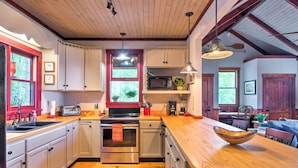 A kitchen with white cabinets, stainless steel appliances, a wooden countertop, and a red rug. - Woodsy Bryson City Cabin w/ Smoky Mountain Views! (Bryson City)