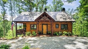 A wooden cabin with a metal roof, surrounded by trees and a gravel driveway. - Woodsy Bryson City Cabin w/ Smoky Mountain Views! (Bryson City)