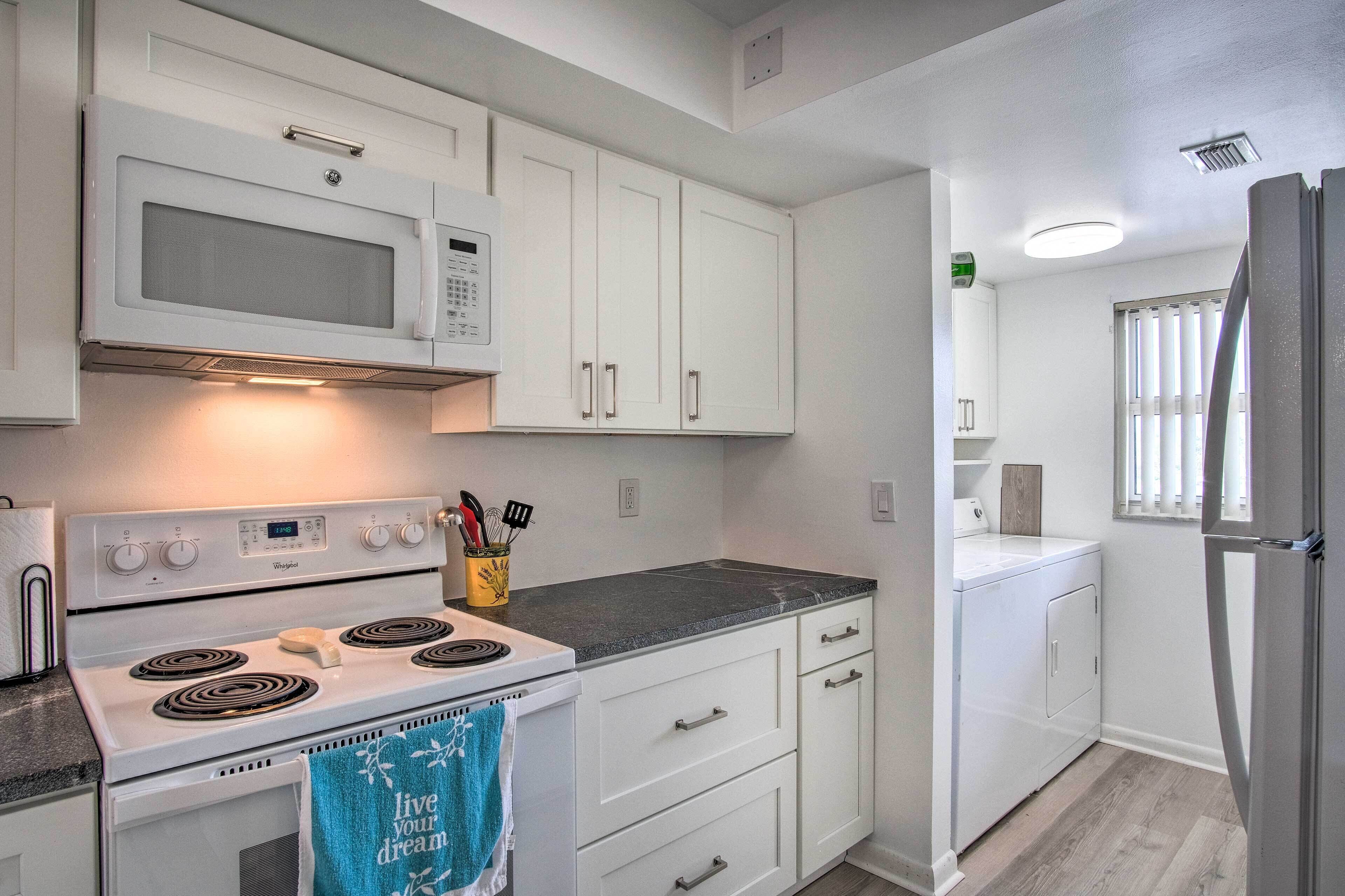 A kitchen with white cabinets, a microwave, a stove, and a refrigerator.