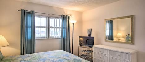 A bedroom with a bed, a dresser, a television, and a mirror.
