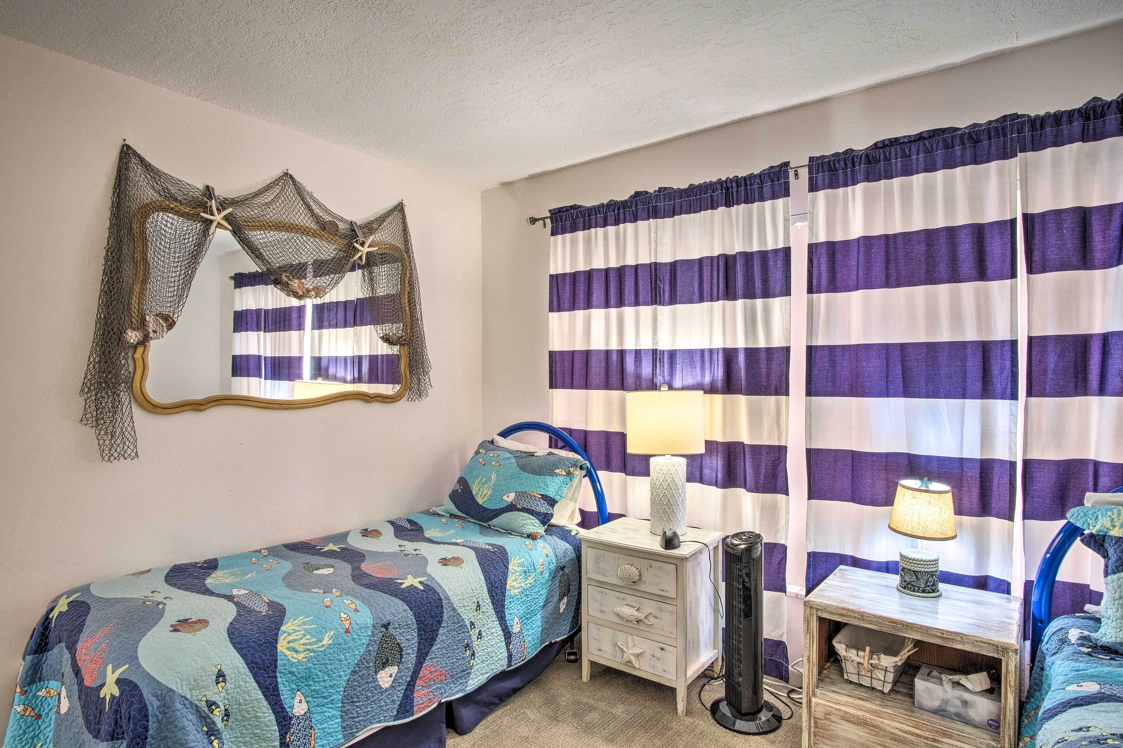 A bedroom with a bed, a nightstand, a lamp, and curtains.