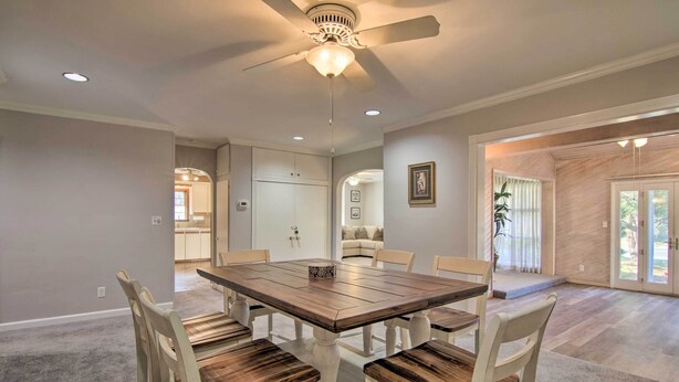 Un coin repas avec une table et des chaises en bois, un ventilateur de plafond et une vue sur l’extérieur.