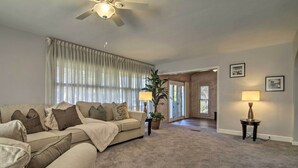 Un salon avec un canapé beige, un ventilateur de plafond, une plante en pot et une lampe.