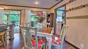 A dining area with a wooden table and chairs, a vase with flowers, and a view through the window. - Pet-friendly Home w/ Deck in Broken Bow! (Broken Bow)