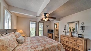 A bedroom with a large bed, wooden dresser, ceiling fan, and a TV. - Ruidoso Home w/ Private Wet Bar & Pool Table (Ruidoso)