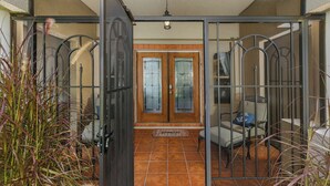 A glass-enclosed patio with a tiled floor, a wooden door with glass panels, and a ceiling fan.