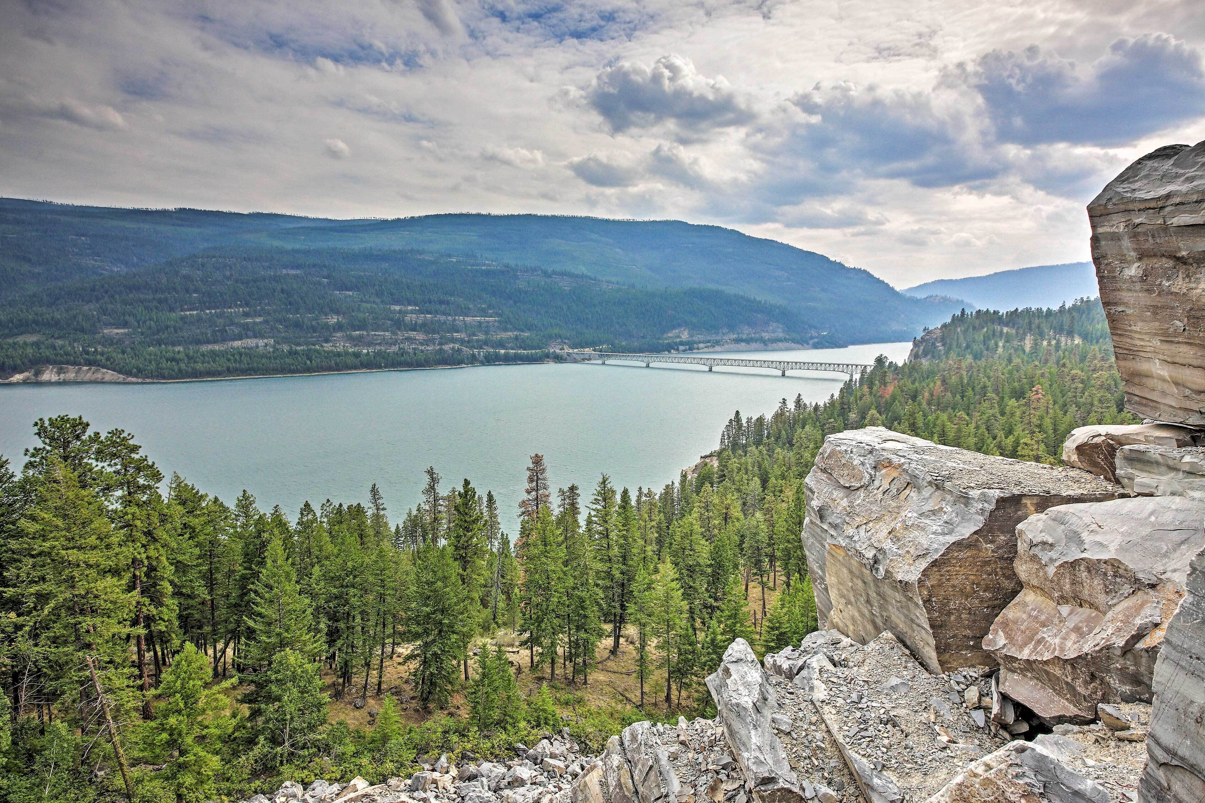 A mountainous landscape with a lake, a bridge, and a rocky outcrop.