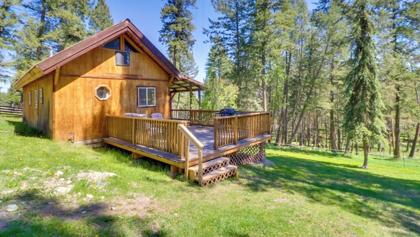 Una baita di legno con veranda, circondata da alberi.
