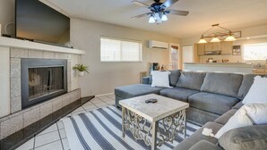 A living room with a fireplace, a sofa, a coffee table, and a ceiling fan. - Beautiful Phoenix Vacation Rental w/ Private Pool! (Phoenix)