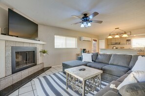 Un salon avec une cheminée, un canapé, une table basse et un ventilateur de plafond.
