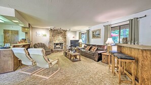 Ein gemütliches Wohnzimmer mit Steinwand, Kamin, Ledersofa, Holztisch und einer Barbereich.