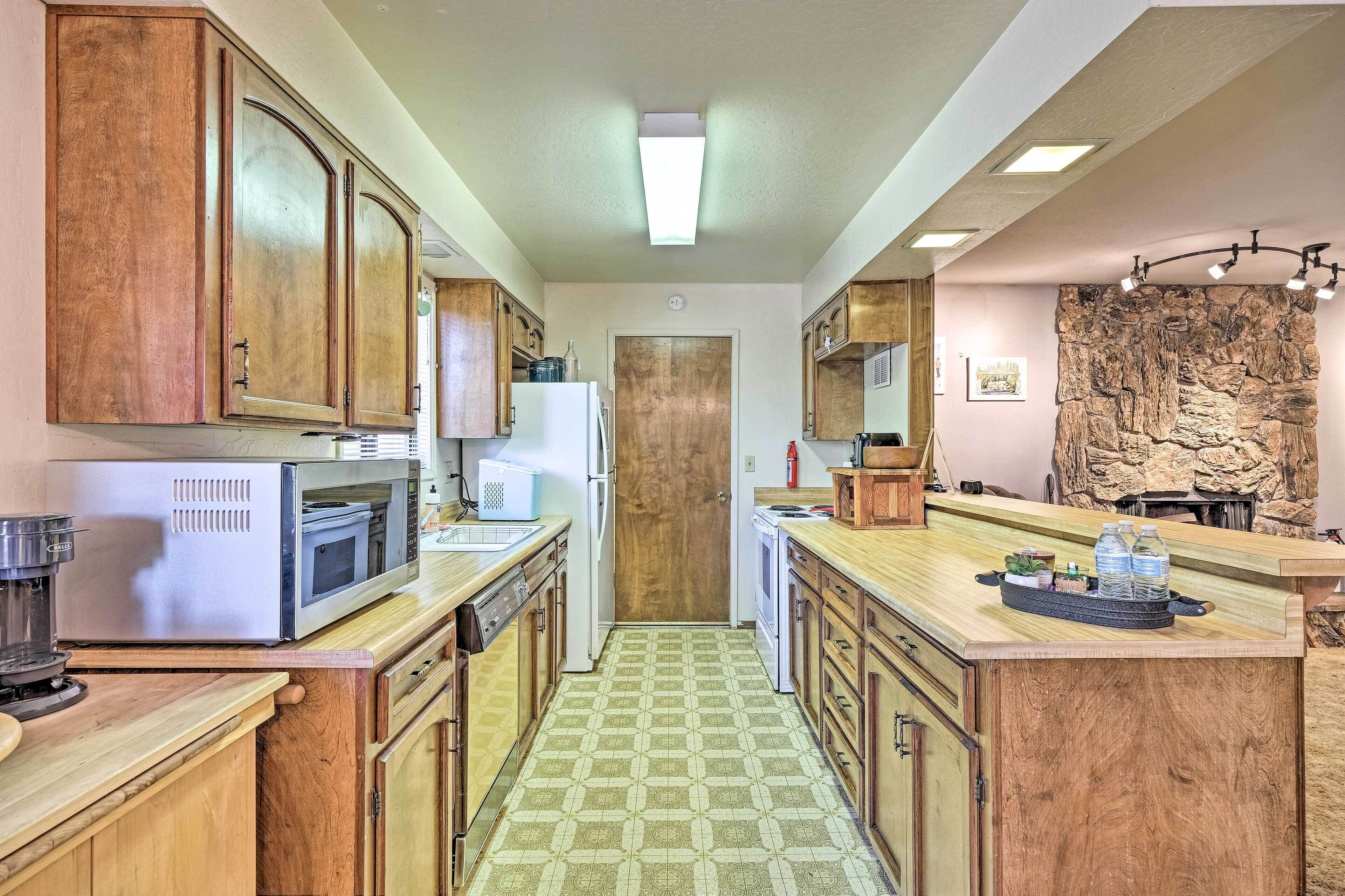A compact kitchen with wooden cabinets, a microwave, a refrigerator, and a coffee maker.