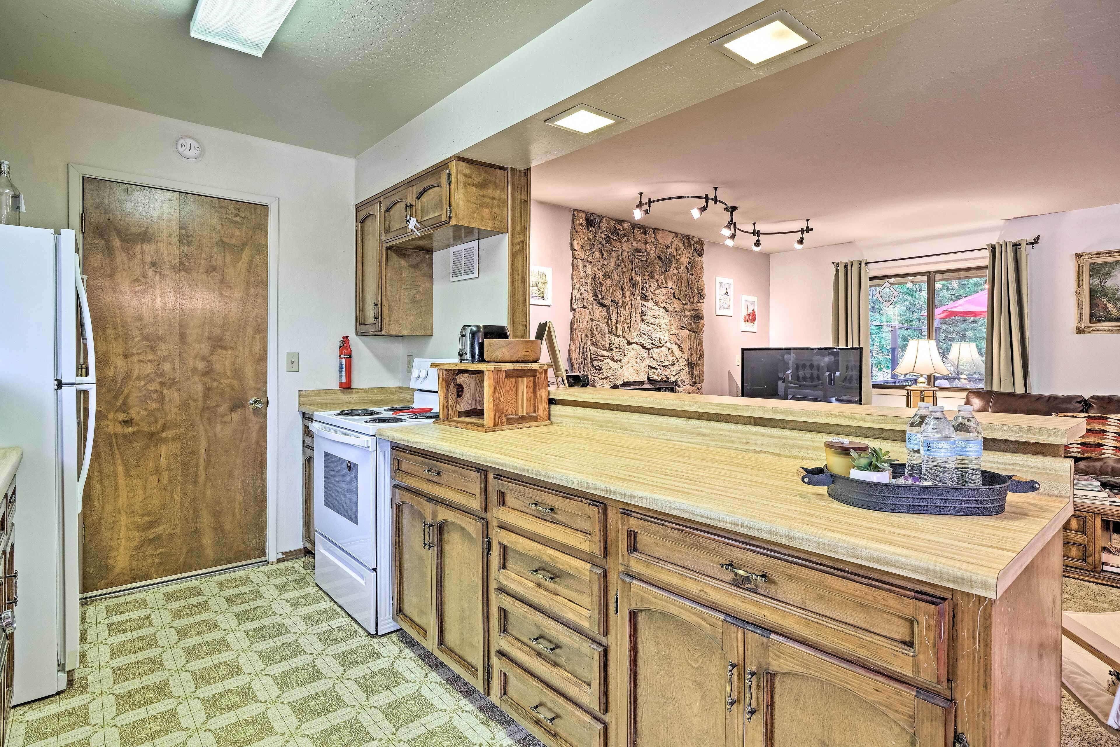 A kitchen with wooden cabinets, a central island, a stove, and a refrigerator.
