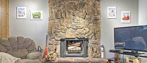 A living room with a stone fireplace, a large flat-screen TV, and a cozy couch.