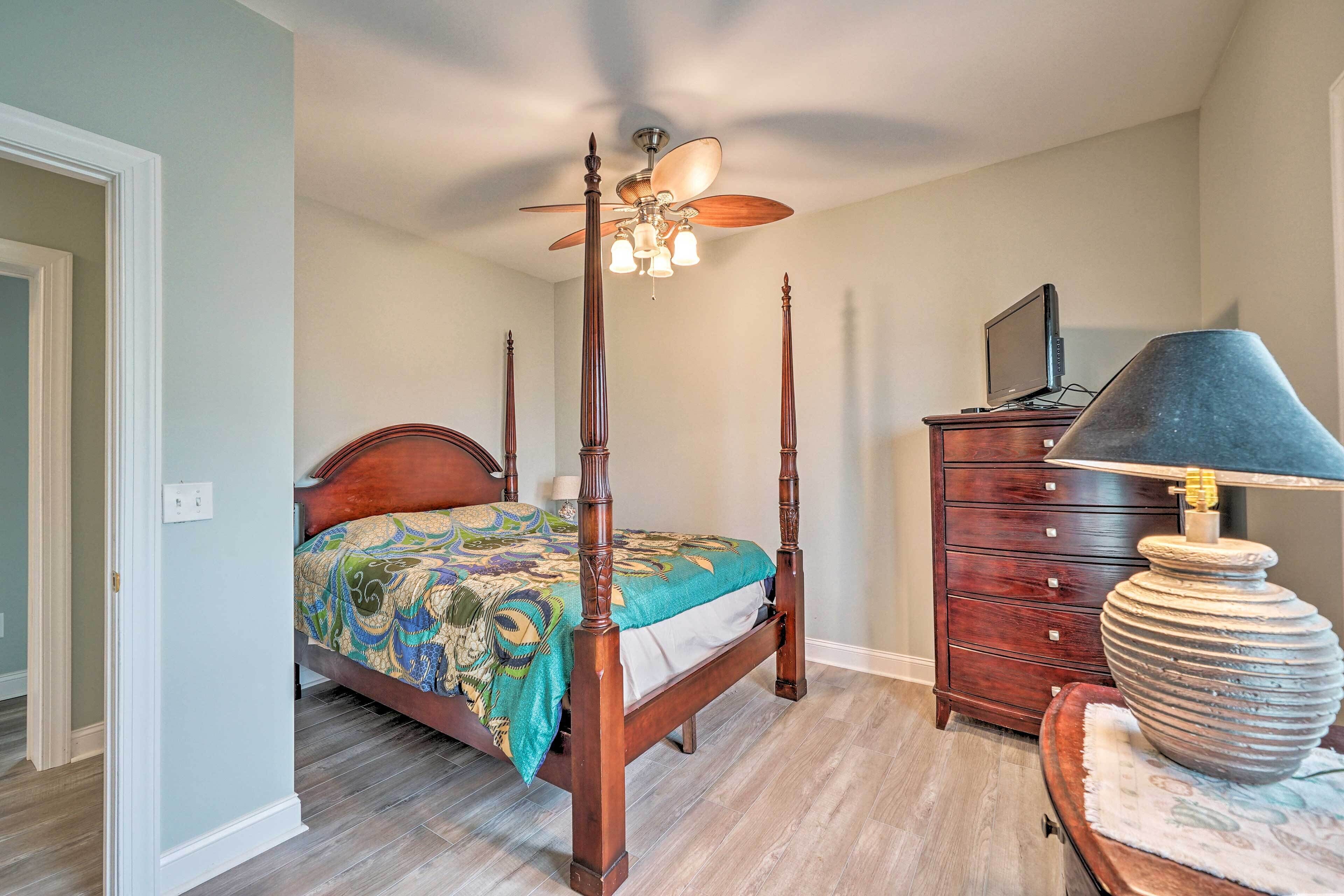 Une chambre à coucher avec un lit à baldaquin, un ventilateur de plafond, une commode et une lampe.