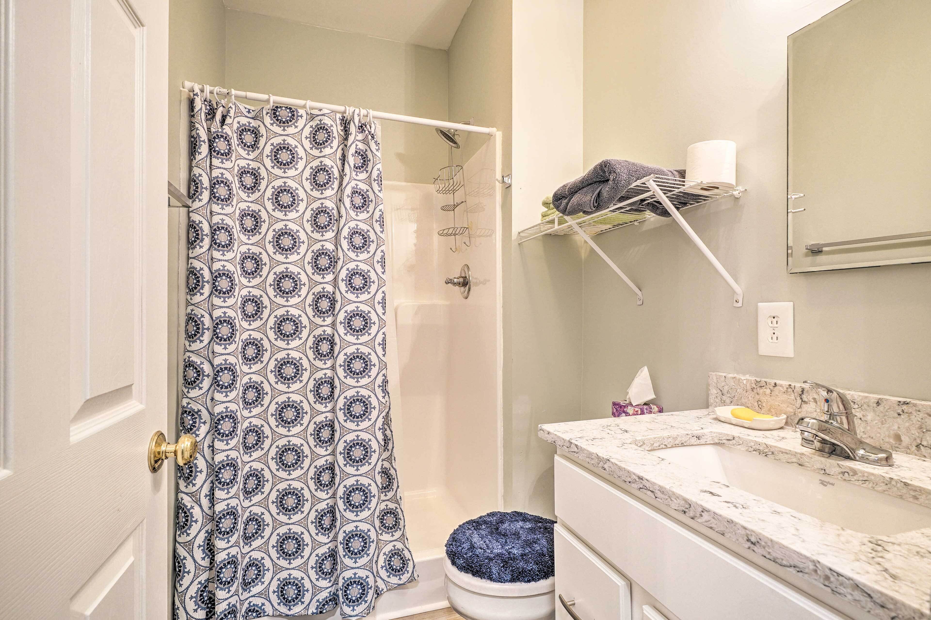 Un baño con cortina de ducha, toallero, lavamanos e inodoro.