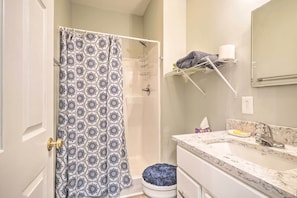 A bathroom with a shower curtain, a towel rack, a sink, and a toilet.