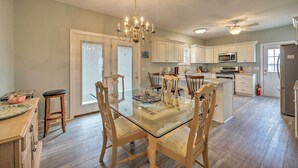 A spacious kitchen with white cabinets, a glass dining table, and a chandelier. - Updated Family Getaway: Walk to Sea Haven Beach! (Sneads Ferry)