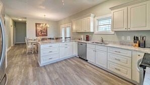 A spacious kitchen with white cabinetry, a central island, and a ceiling fan. - Updated Family Getaway: Walk to Sea Haven Beach! (Sneads Ferry)