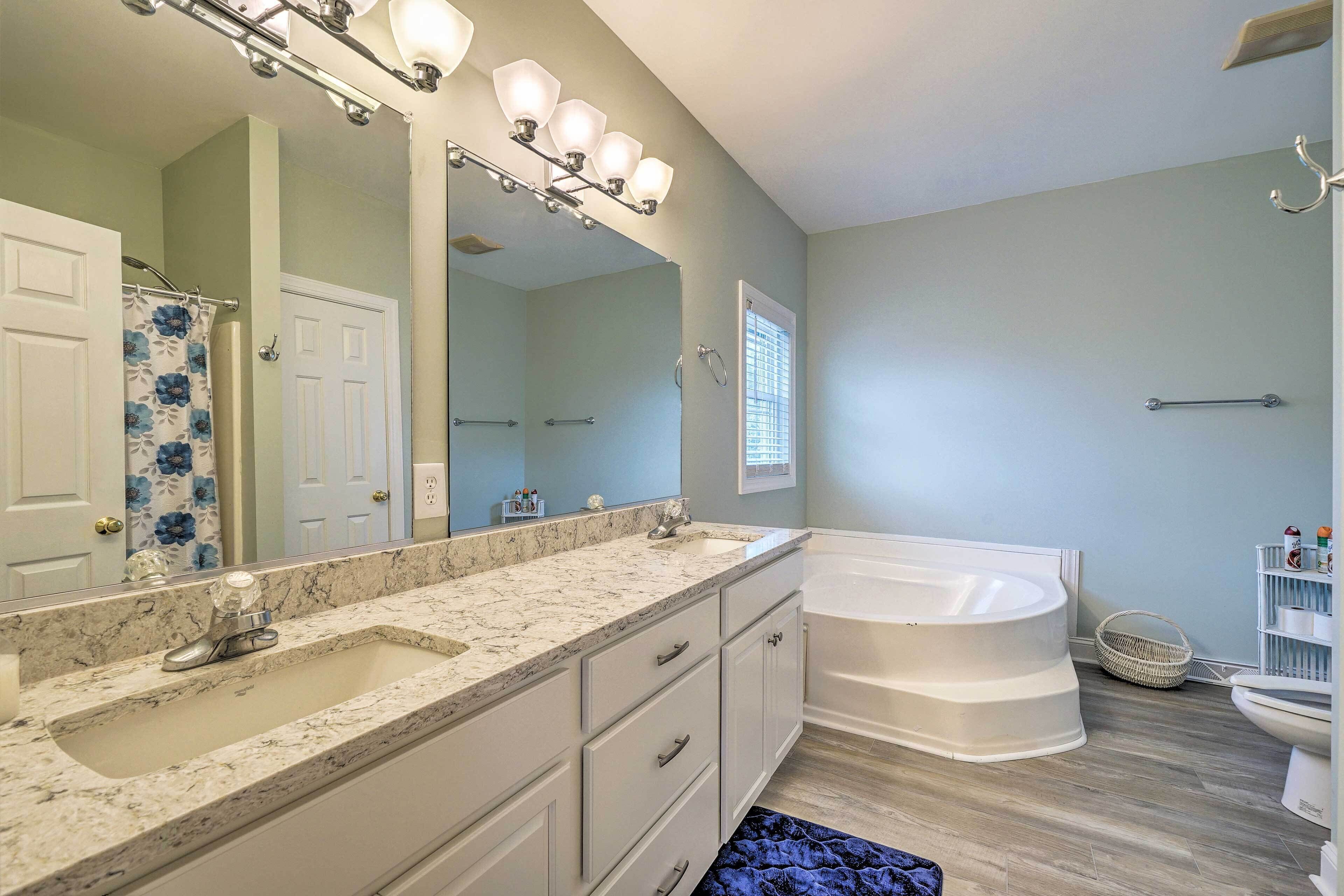 A bathroom with a large mirror, two sinks, a bathtub, and a shower.
