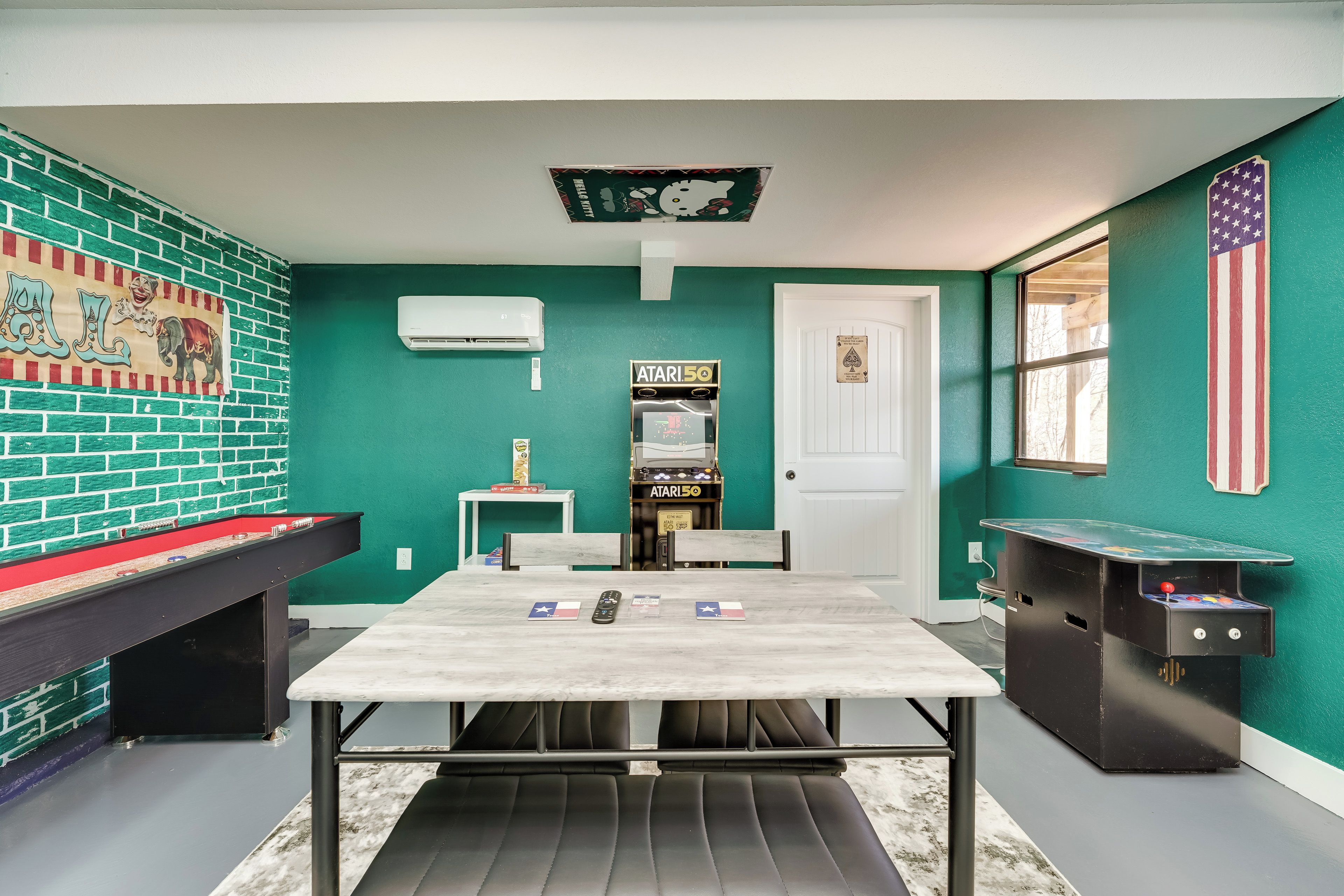 A room with a pool table, an Atari 2600 console, a small table with a card game, and a mural with cartoon characters.