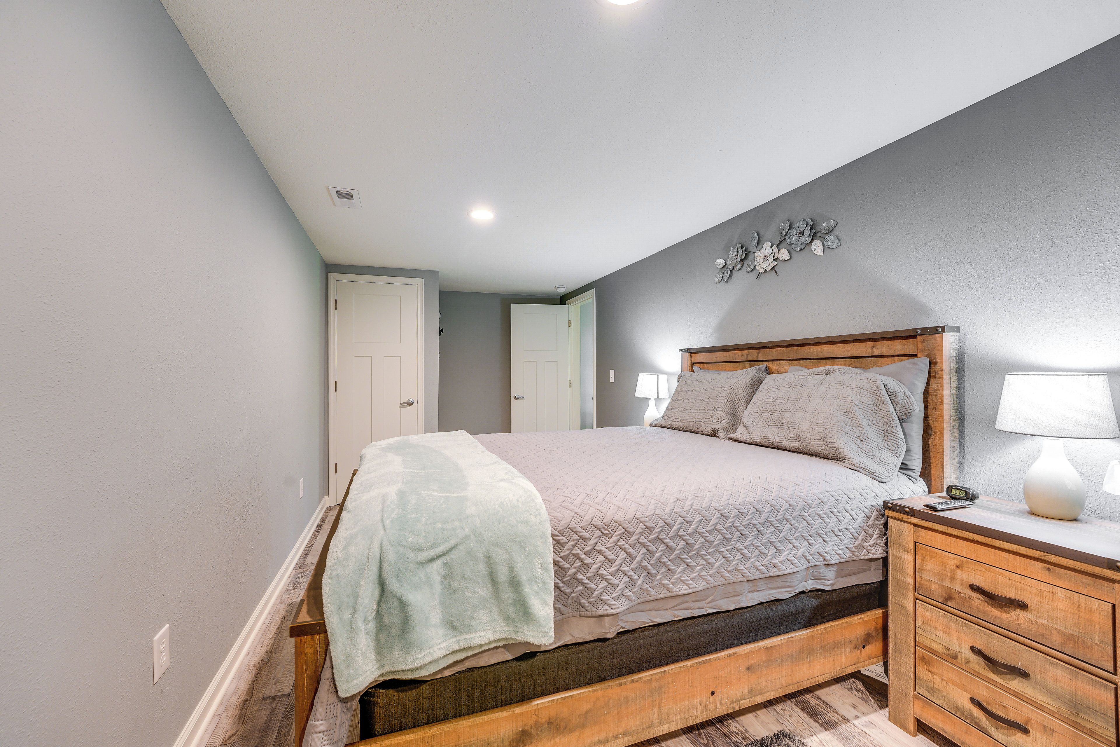 A bedroom with a wooden bed, a nightstand, and a wall-mounted lamp.