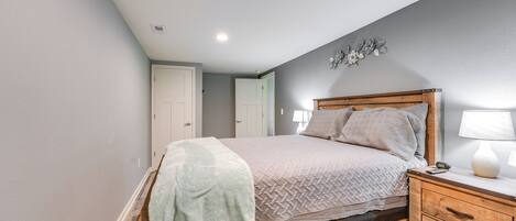 A bedroom with a wooden bed, a nightstand, and a wall-mounted lamp.