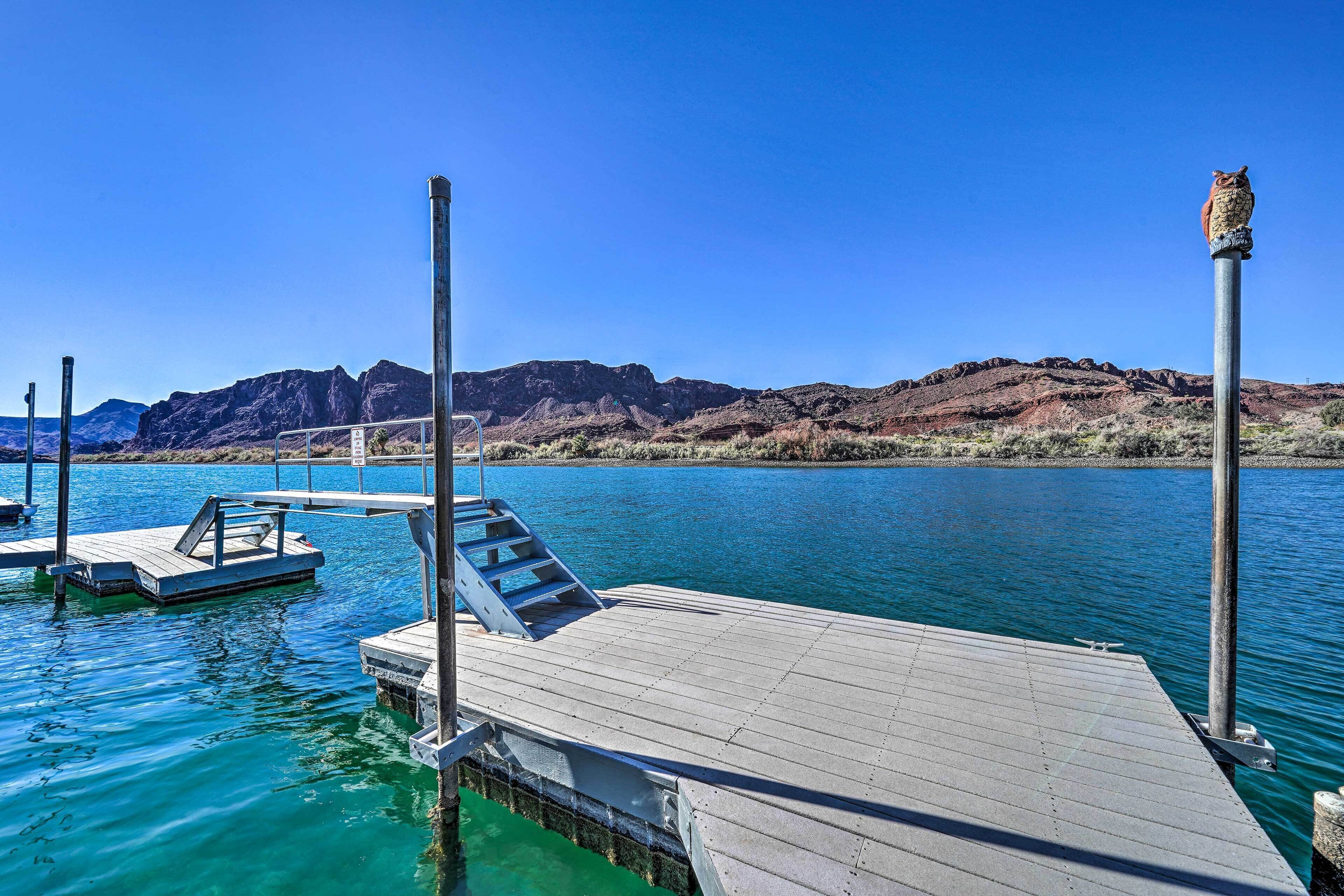 A dock extending into a calm body of water with a mountainous backdrop.