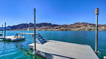 A dock extending into a calm body of water with a mountainous backdrop.