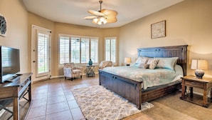 A bedroom with a bed, bedside tables, a TV, and a ceiling fan. - 11 Mi to Phoenix Raceway: Luxury Sonoran Oasis! (Goodyear)