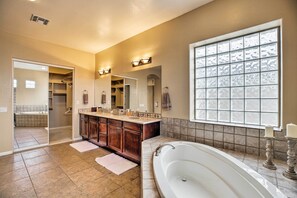 A spacious bathroom with a large bathtub, double vanity with a mirror, and a walk-in closet. - 11 Mi to Phoenix Raceway: Luxury Sonoran Oasis! (Goodyear)