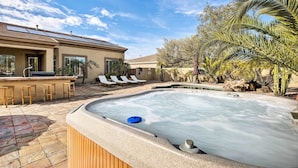 A hot tub with a stone surround, a bar area with stools, and a poolside lounge with chairs. - 11 Mi to Phoenix Raceway: Luxury Sonoran Oasis! (Goodyear)
