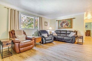 A spacious living room with leather sofas, a wooden coffee table, and a large window providing natural light. - ~ 10 Mi to Dtwn: Indianapolis Home w/ Game Room! (Indianapolis)