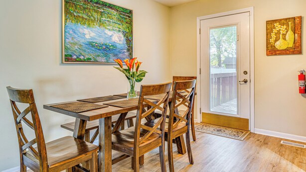 A dining area with a wooden table and chairs, a vase with flowers, and two paintings on the walls. - ~ 10 Mi to Dtwn: Indianapolis Home w/ Game Room! (Indianapolis)