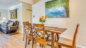 A dining area with a wooden table and chairs, a painting of a landscape, and a sofa in the background. - ~ 10 Mi to Dtwn: Indianapolis Home w/ Game Room! (Indianapolis)