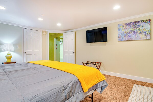 A bedroom with a bed, a television, and a painting on the wall.