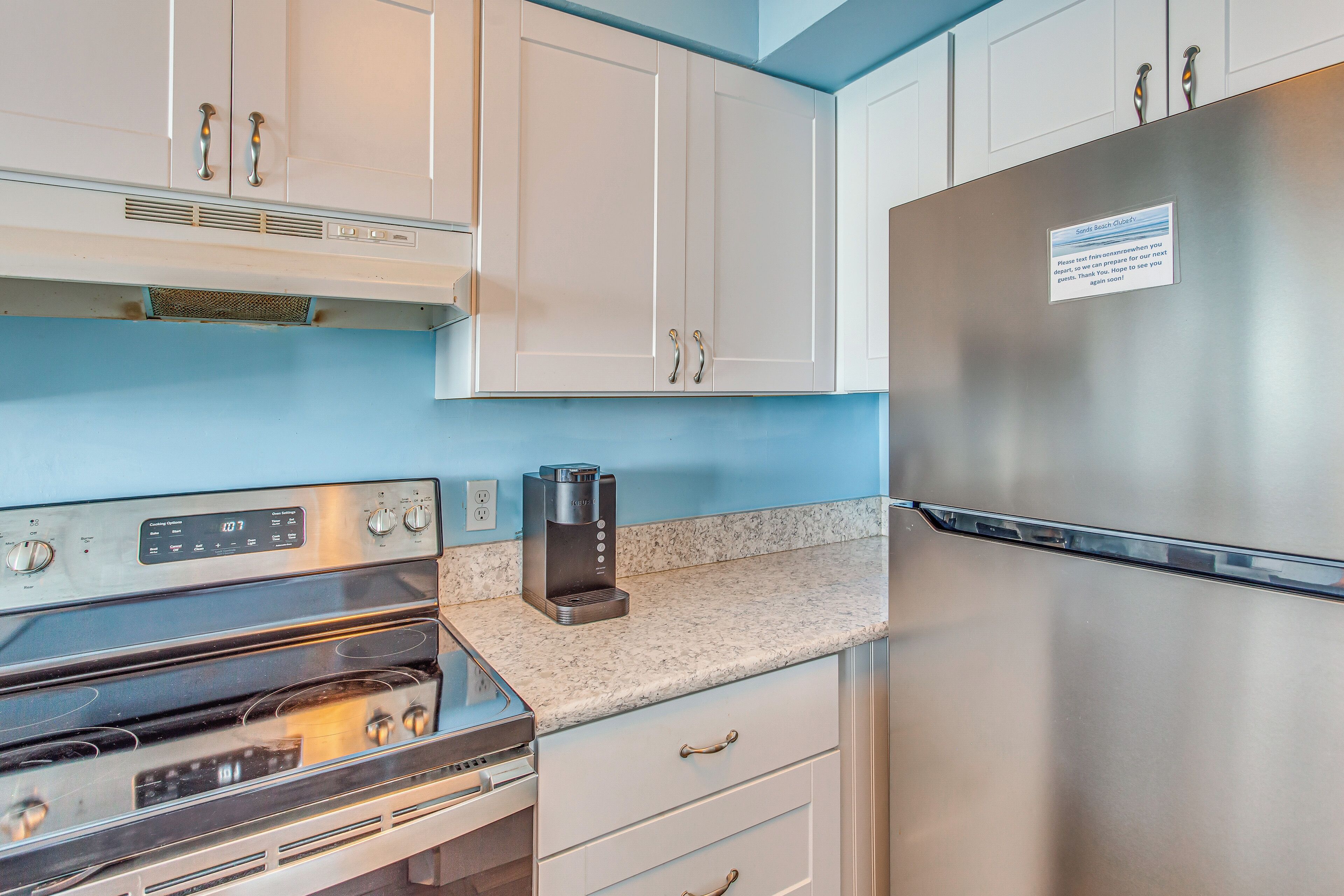 A kitchen with a stainless steel refrigerator, a coffee maker, and a built-in oven.