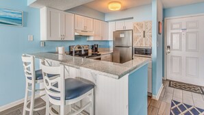 A kitchen with white cabinets, a stainless steel refrigerator, and a marble countertop. - Oceanfront Myrtle Beach Condo With Resort Perks! (Myrtle Beach)
