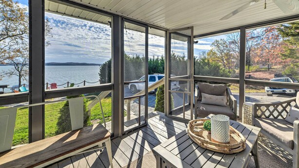 A covered outdoor area with large windows, wooden deck, and seating.
