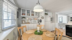 A dining area with a wooden table, woven placemats, and a hanging light fixture.