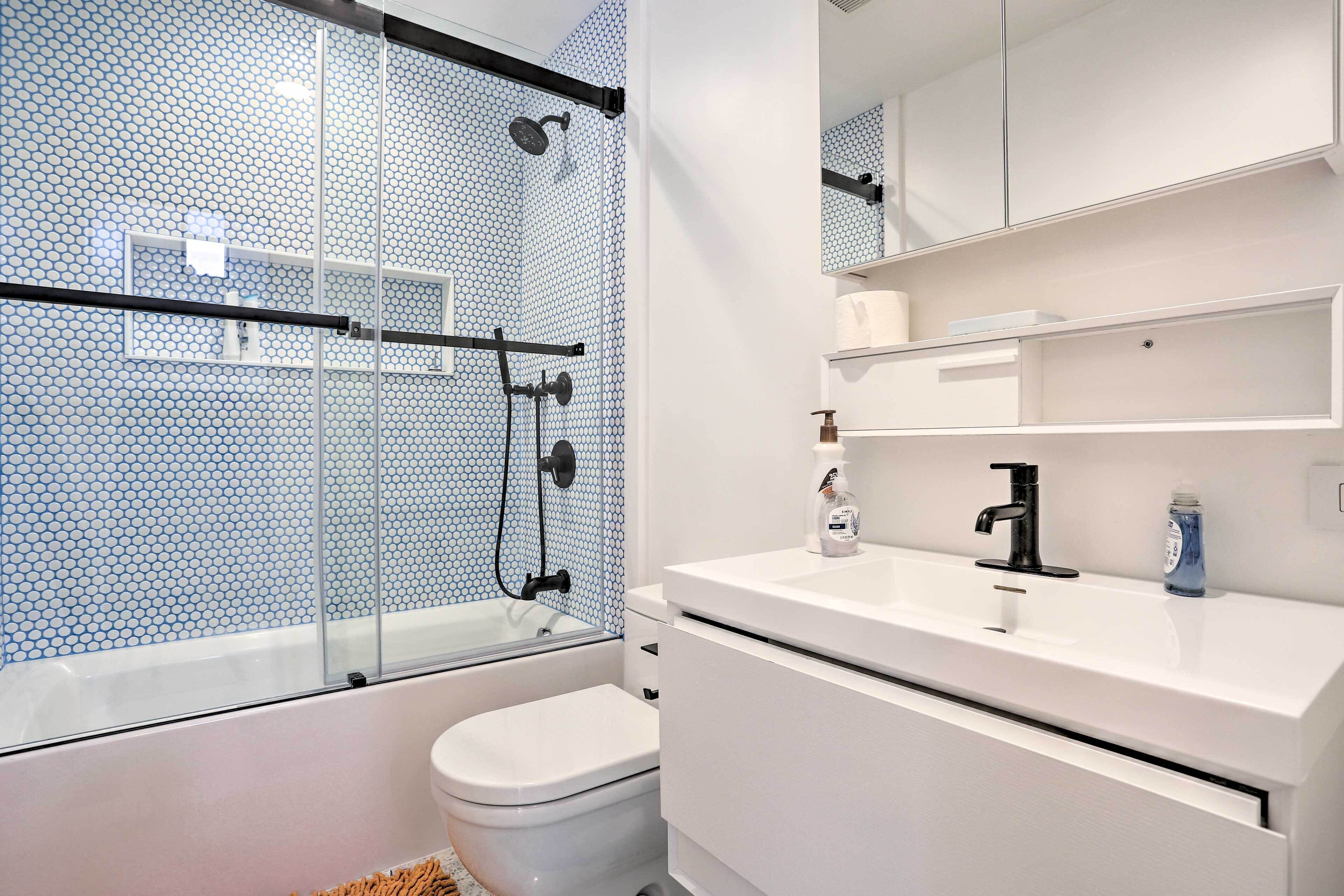 A modern bathroom with a glass-enclosed shower, a white toilet, and a white sink with a mirror above it.