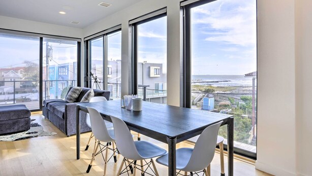 A modern living room with a dining area, large windows, and a view of the sea. - Luxury Long Beach Villa With Ocean Views! (Long Beach)
