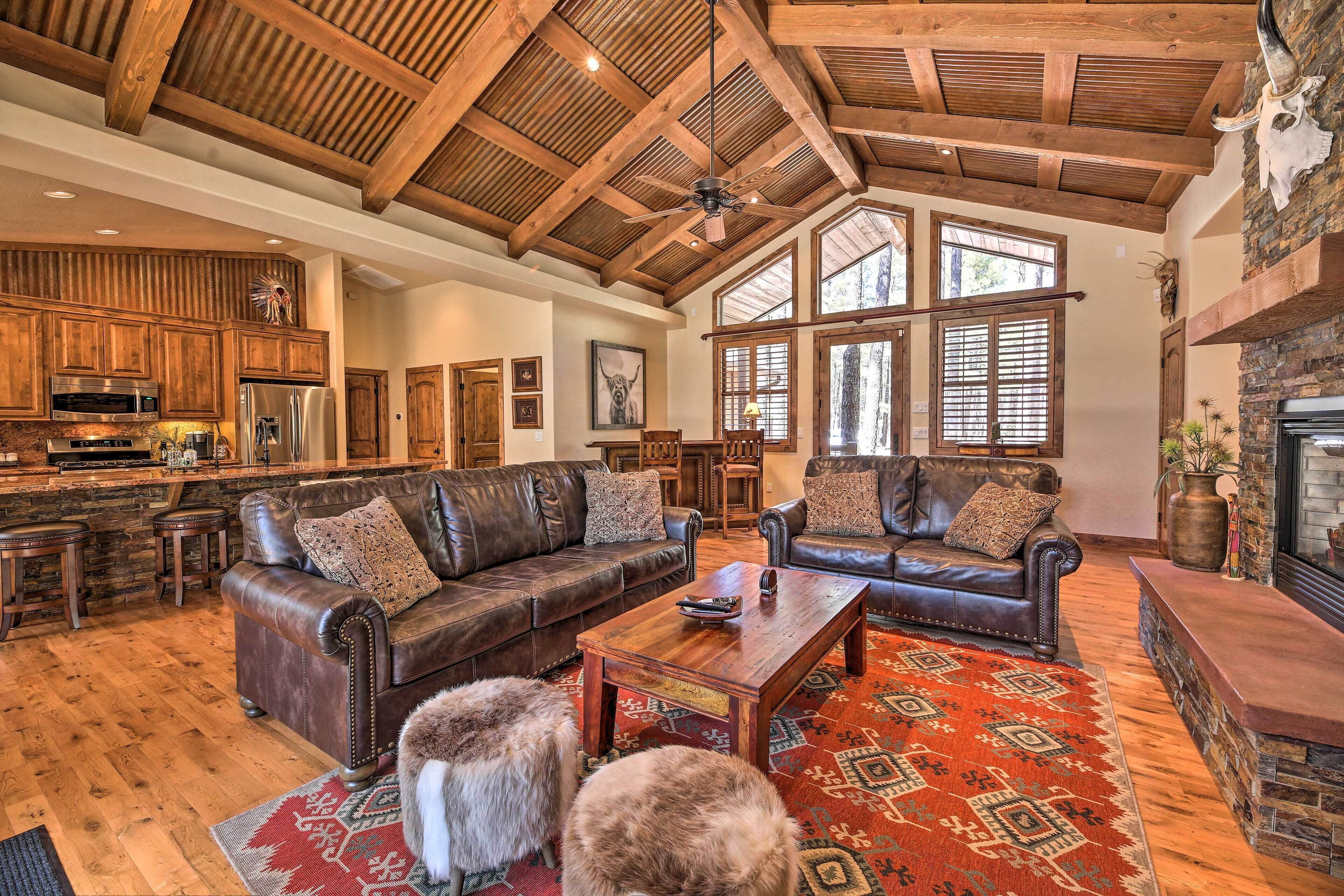 A spacious living area with leather sofas, a wooden coffee table, and a stone fireplace.