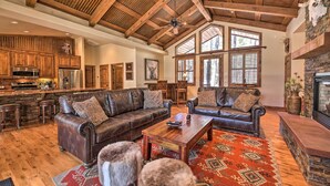 A spacious living area with leather sofas, a wooden coffee table, and a stone fireplace. - Fire Pit: Family-friendly Lakeside Retreat (Lakeside)