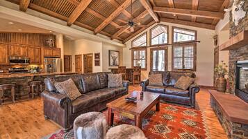 A spacious living area with leather sofas, a wooden coffee table, and a stone fireplace.