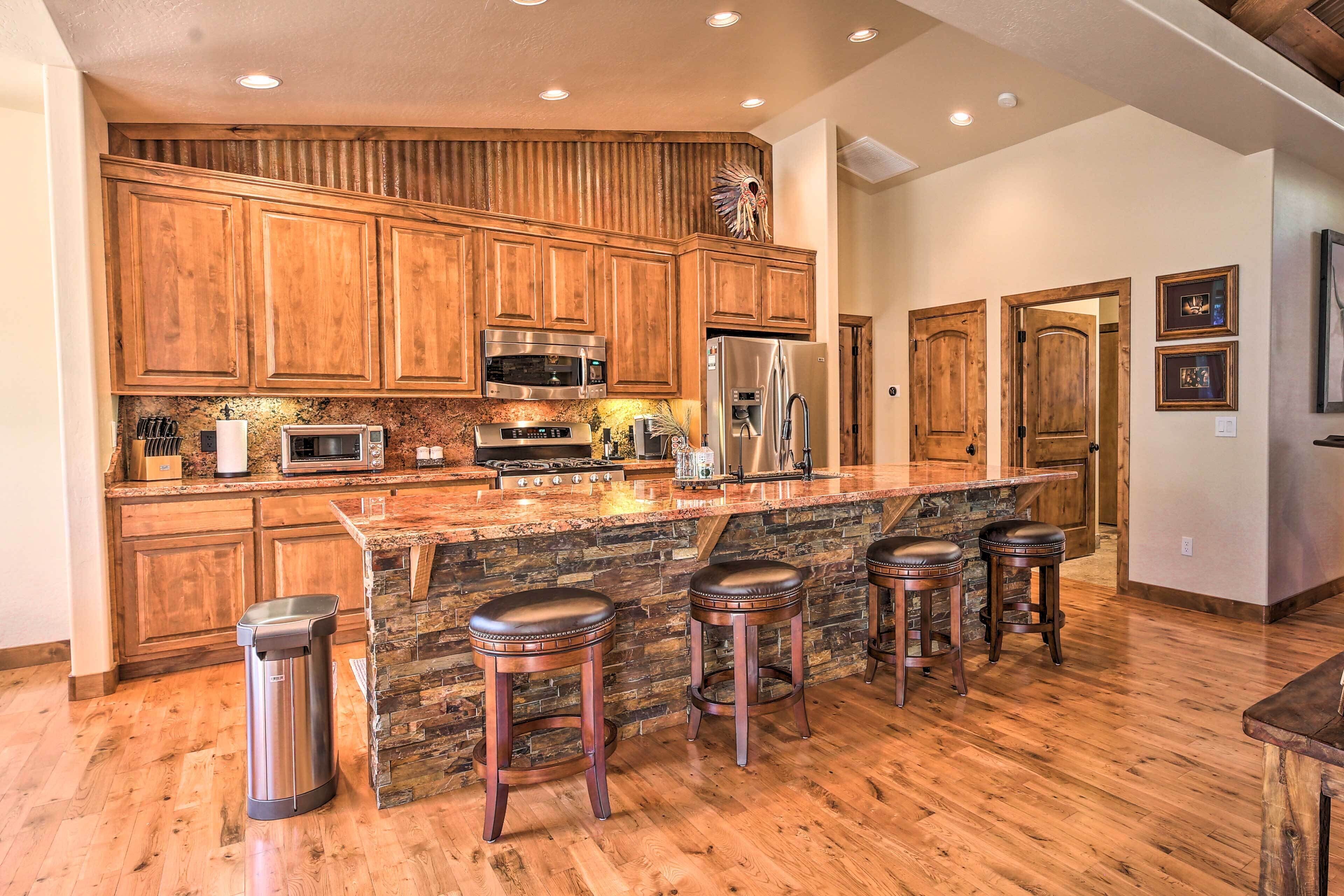 A kitchen with wooden cabinets, a stone island, stainless steel appliances, and a trash can.