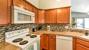 A kitchen with wooden cabinets, a white stove, a microwave, and a dishwasher. - Serene Surprise Home w/ Backyard & Private Pool (Surprise)