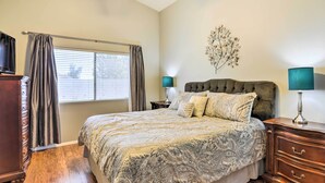 A bedroom with a large bed, wooden dresser, and a nightstand with lamps. - Serene Surprise Home w/ Backyard & Private Pool (Surprise)
