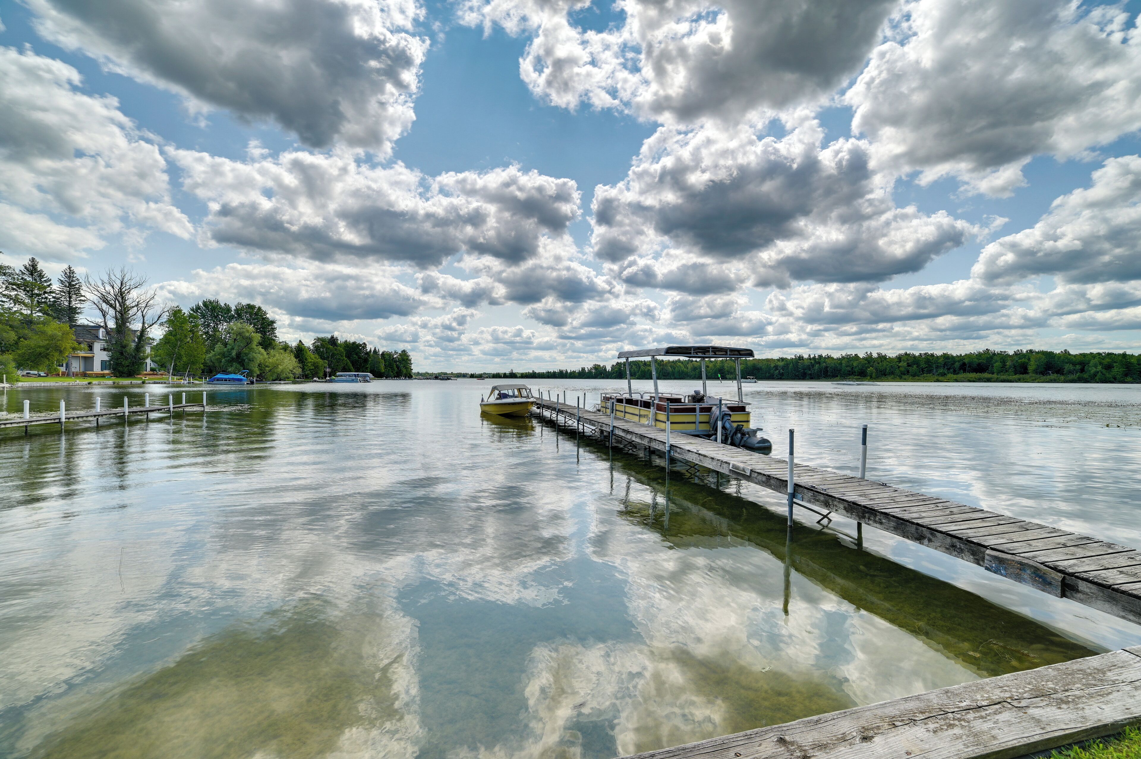A calm lake with a dock and a boat.